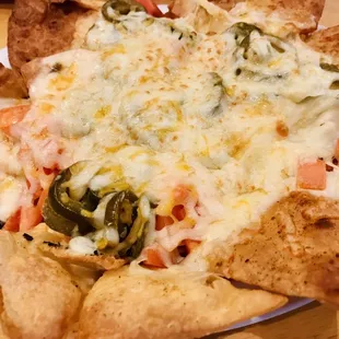 a plate of nachos with cheese and jalapenos