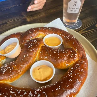 a large pretzel with dipping sauces