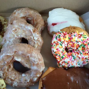 Three whole wheat glazed, strawberry jelly filled, cake with sprinkles and Bismarck.