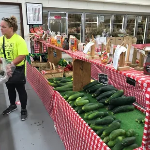 a woman standing in front of a display of cucumbers