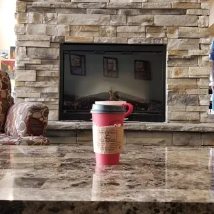 a coffee cup on a coffee table in front of a fireplace
