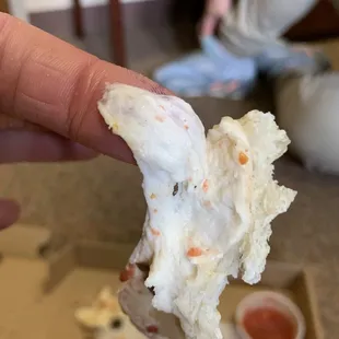 a hand holding a piece of pizza