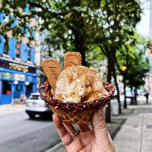 a hand holding a waffle cone filled with ice cream