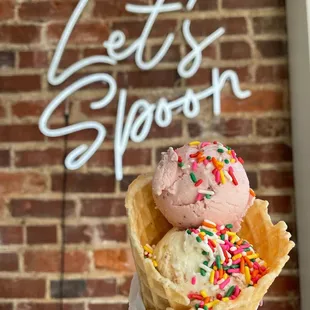a hand holding a cone of ice cream with sprinkles