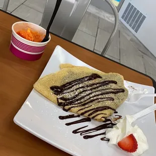 a crepe on a plate with chocolate sauce and strawberries