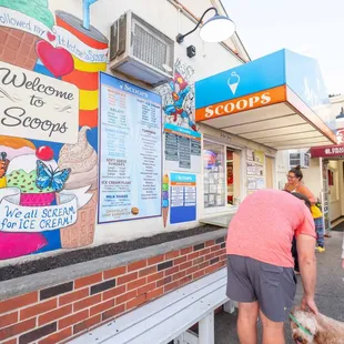 two people and a dog in front of a ice cream shop