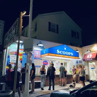 a group of people standing outside of a store at night