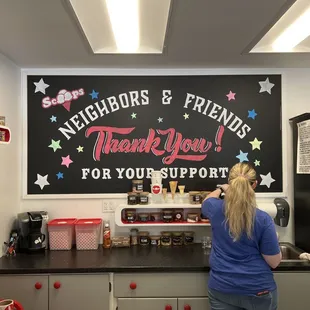 a woman standing in front of a sign that says thank you for your support