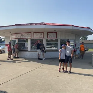 two people standing in front of a small ice cream shop