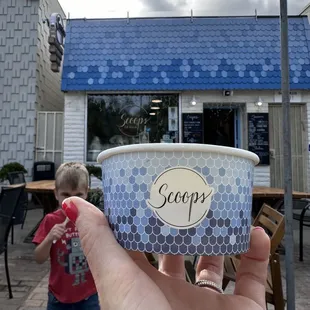 a hand holding a cup of ice cream