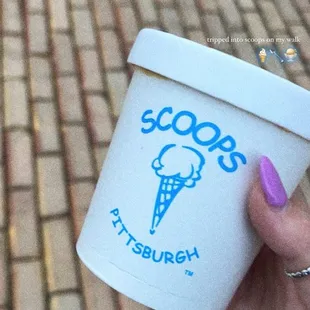 a hand holding a cup of ice cream