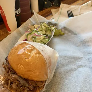 Brisket sandwich on regular bun with onion and cucumber German salad with lemonade