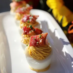 Deviled Eggs topped with candied bacon and pickled shallots