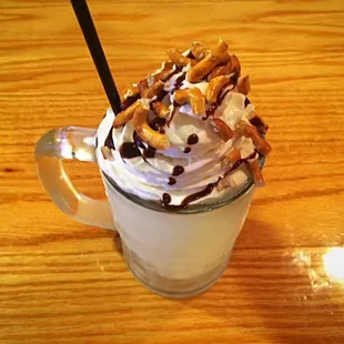 a chocolate milkshake topped with whipped cream and pretzels