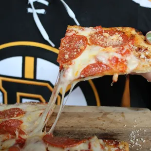 a person taking a slice of pizza