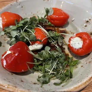 a plate of tomatoes and greens on a wooden table