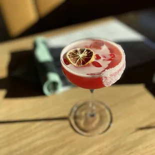 a red cocktail in a coupe glass