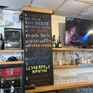 a bar with a chalkboard menu on the wall