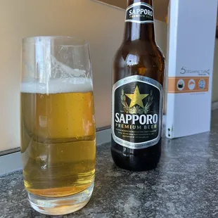 a bottle of sapporo beer next to a glass of beer