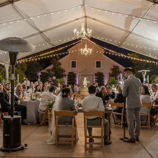 a group of people sitting at tables under a tent