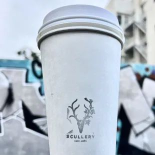 a cup of coffee in front of graffiti