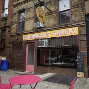 a pink table and chairs in front of a sandwich&apos;s bakery