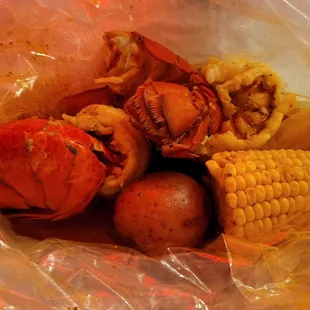 Bag opened. 2 lobster tails, a potato and a cob of corn. Seasoned with special cajun seasoning.