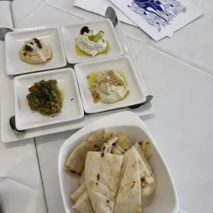 a plate of pita chips, a bowl of hummus and a plate of hummus