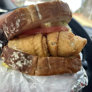 Flounder sandwich on wheat bread with lettuce, tomatoes and mustard.