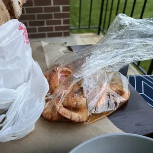 a sandwich wrapped in plastic and next to a bowl of soup