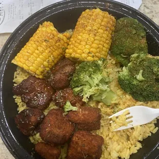 Salmon bites with rice, crown, and broccoli. The salmon bites are drizzled in a jerk sauce