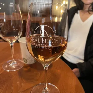 a woman sitting in front of a glass of wine