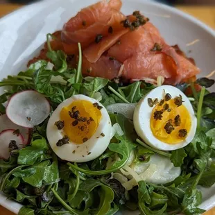 a plate of salad with hard boiled eggs, radishes, and smoked salmon