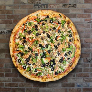 a whole pizza on a brick wall