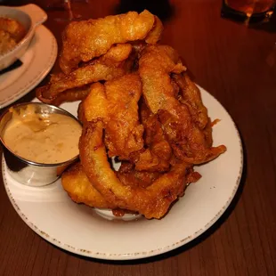 a plate of onion rings and dipping sauce
