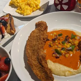 Clockwise: cheese eggs, fish and grits, fruit cup, kids meal french toast with chicken sausage.