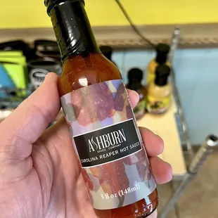 a hand holding a hot sauce