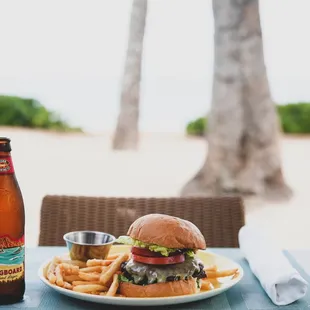 a burger and fries on a plate with a bottle of beer