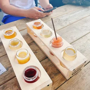 a man sitting at a picnic table with a variety of ciders