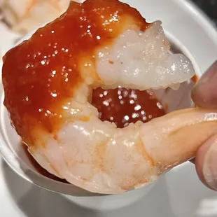 a hand holding a piece of shrimp