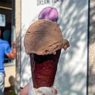 a hand holding a chocolate ice cream cone