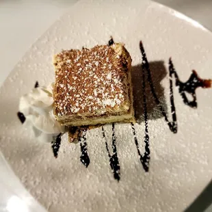 Tiramisu: Ladyfingers dipped in coffee, layered w/whipped eggs, sugar, &amp; mascarpone cheese topped with cocoa powder &amp; drizzled w/chocolate.