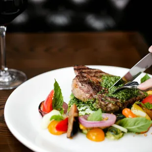 a person cutting a piece of steak