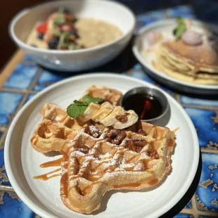 a plate of waffles and a bowl of fruit