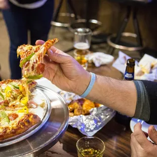 a person taking a slice of pizza