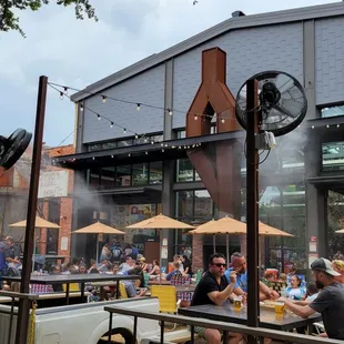 a crowd of people sitting at tables with umbrellas