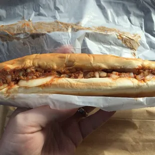 a hand holding a chili dog