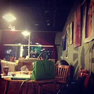 a woman sitting at a table with a green purse