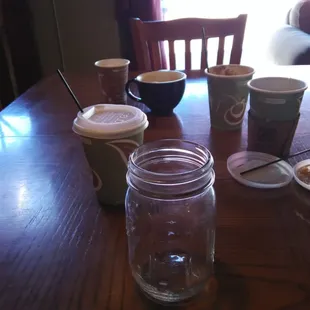 a table with a jar of coffee and two cups of coffee