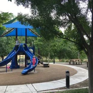 Two of the four picnic tables and grill can be seen next to the playground.